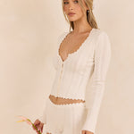 ALT's ivory Wren shorts and matching Lark top, the scalloped hem shown beside a single flower.