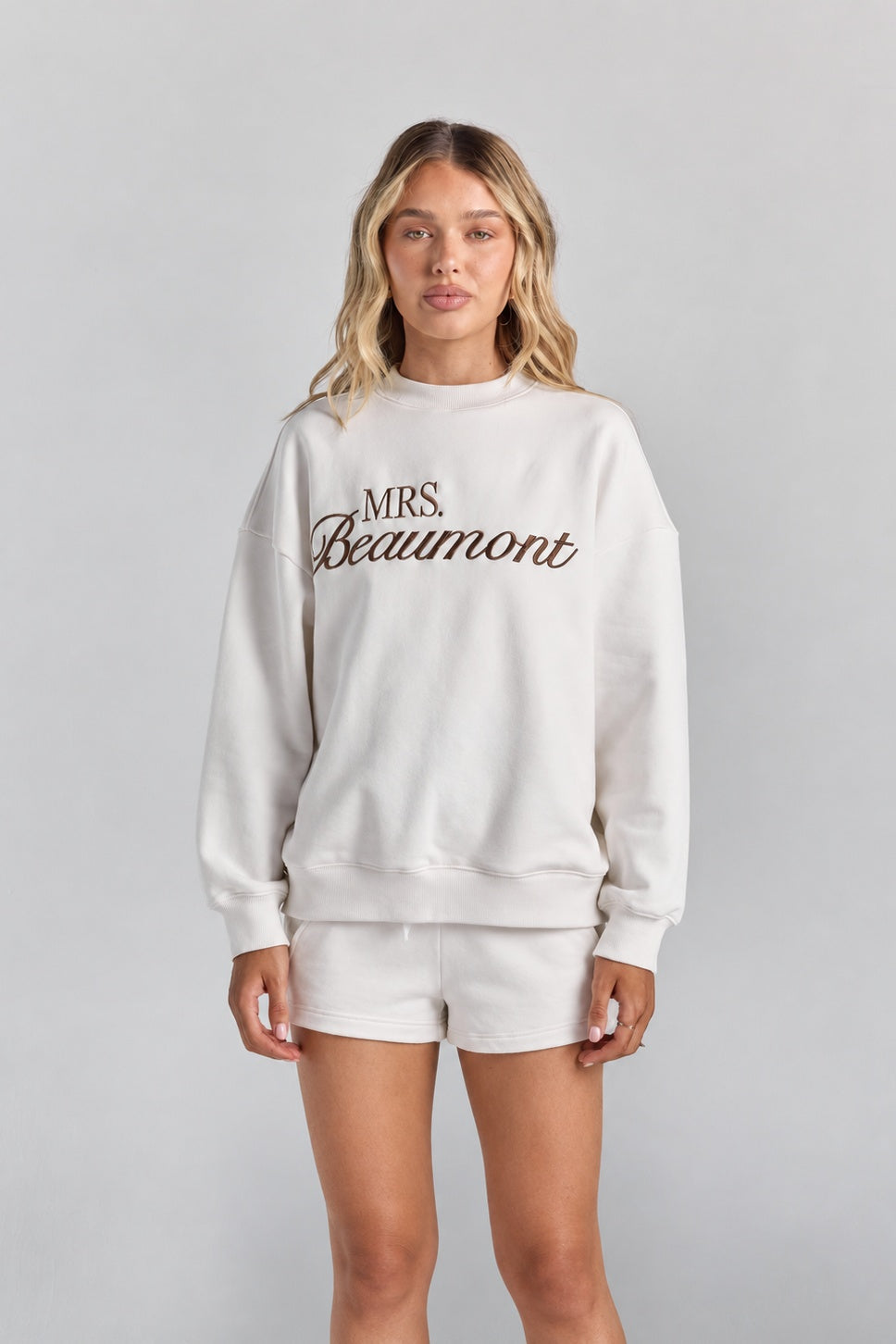 White Althea track short from the front, its drawstring waist and short hem just showing under the Pia crew sweatshirt.