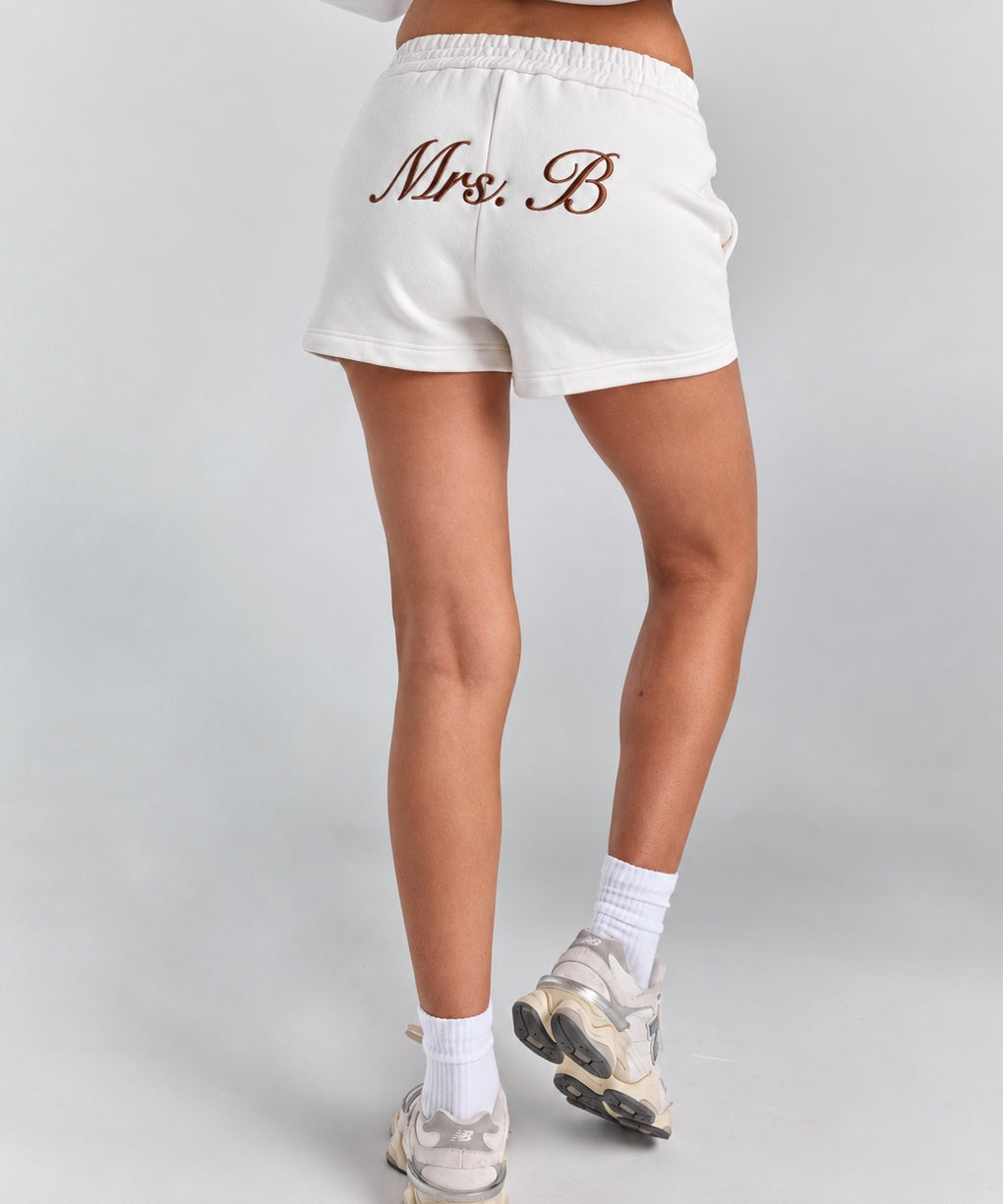 White Althea track short from behind showing the full short length, with personalized embroidery across the back and a curved hem.