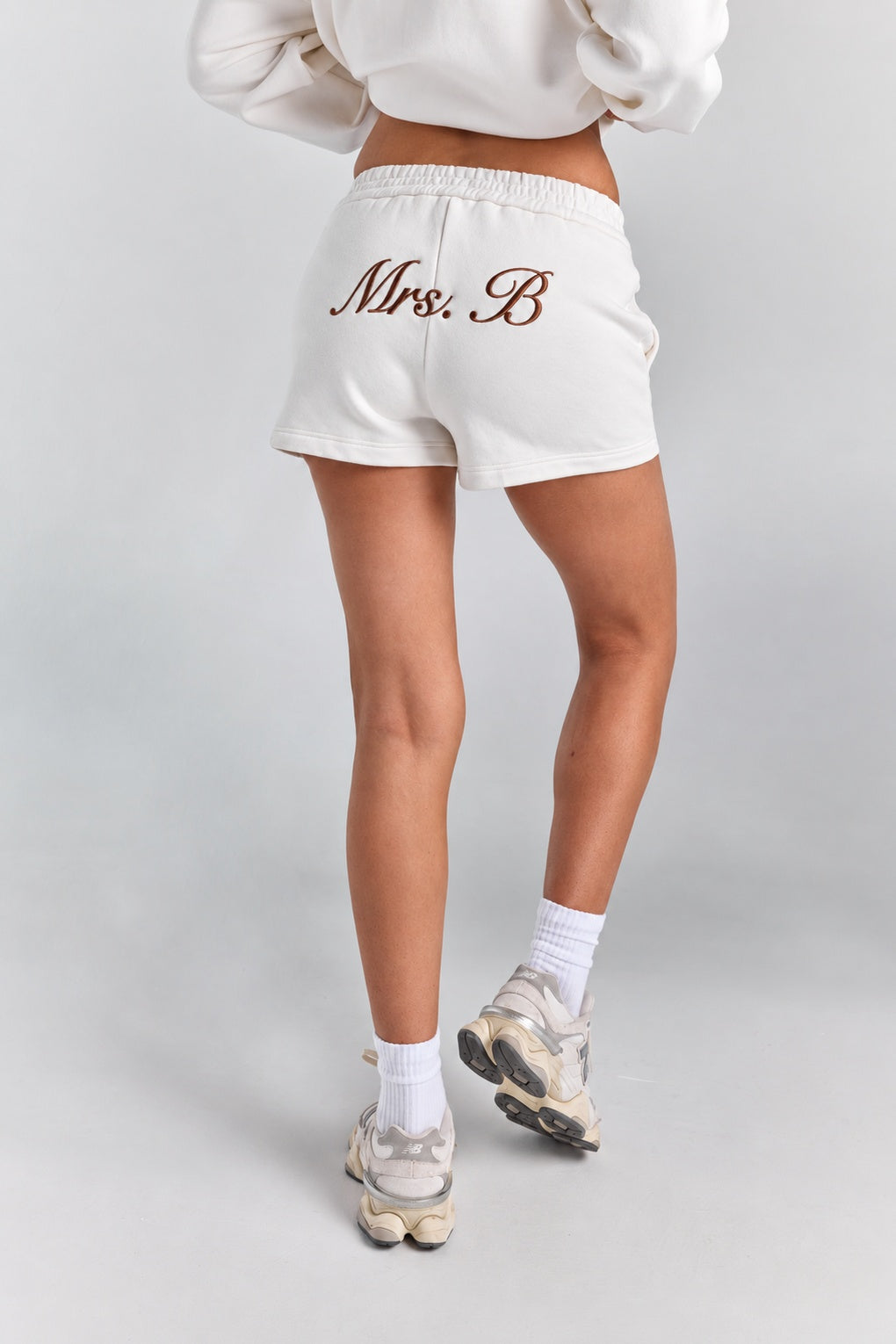 White Althea track short from behind showing the full short length, with personalized embroidery across the back and a curved hem.