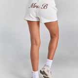 White Althea track short from behind showing the full short length, with personalized embroidery across the back and a curved hem.