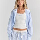 Blue stripe Beatrice drawstring short from the front, with a white ribbon tie, contrast waistband and button front, under the Corinna button-up shirt.