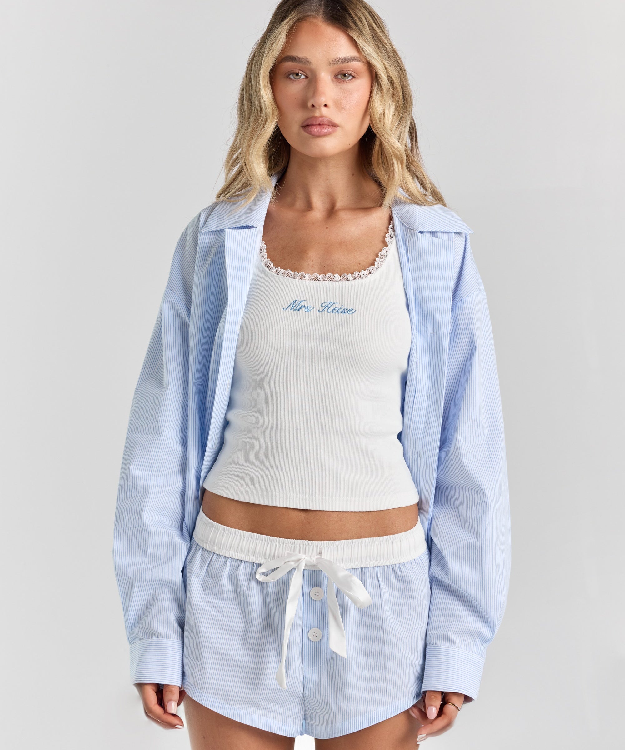 Blue stripe Beatrice drawstring short from the front, with a white ribbon tie, contrast waistband and button front, under the Corinna button-up shirt.