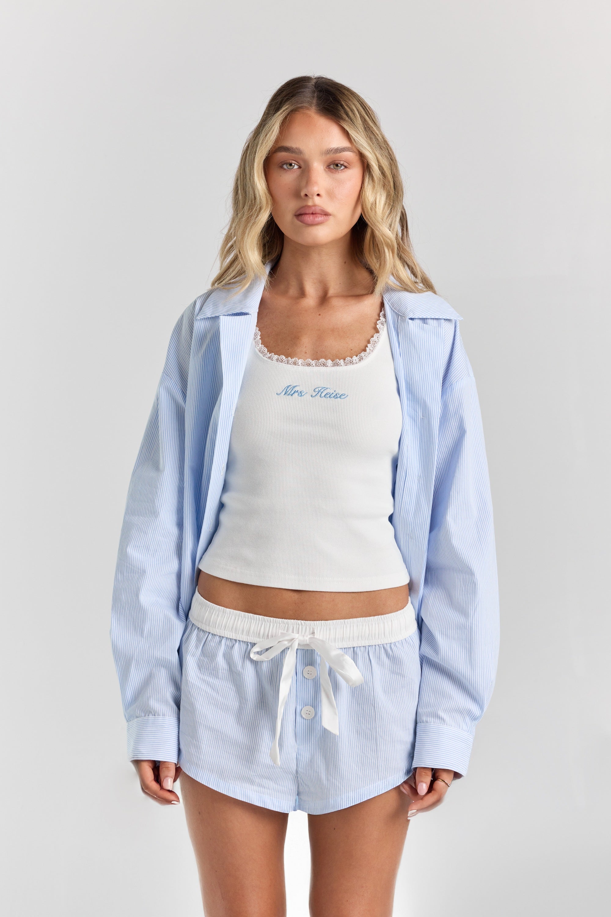 Blue stripe Beatrice drawstring short from the front, with a white ribbon tie, contrast waistband and button front, under the Corinna button-up shirt.
