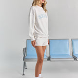 White Bride Althea track short from the side, showing the side seam pocket and short hem beneath the Bride Pia crew sweatshirt.