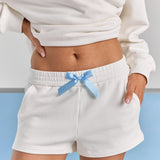 A close-up of the blue satin bow at the elasticated waist of the white Bride Althea track short, with a side pocket.