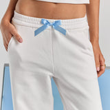 A close-up of the blue satin bow at the elasticated waist of the white Bride Paola trackpant, with a slim side pocket.