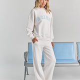 White Bride Pia crew sweatshirt from a three-quarter angle, relaxed with dropped shoulders, BRIDE across the chest and a ribbed hem.