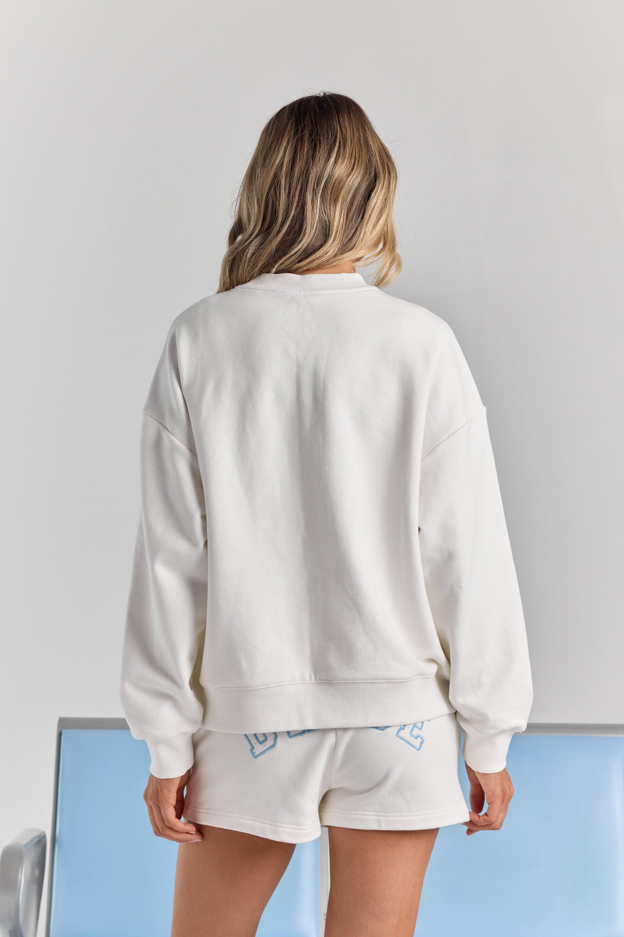 White Bride Pia crew sweatshirt from behind, plain across the back with dropped shoulders and a ribbed neckline, cuffs and hem.
