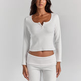 ALT's white Cleo long sleeve top, fitted rib with a scoop neck and short button placket, cropped at the waist above the Frankie foldover ribbed pant.