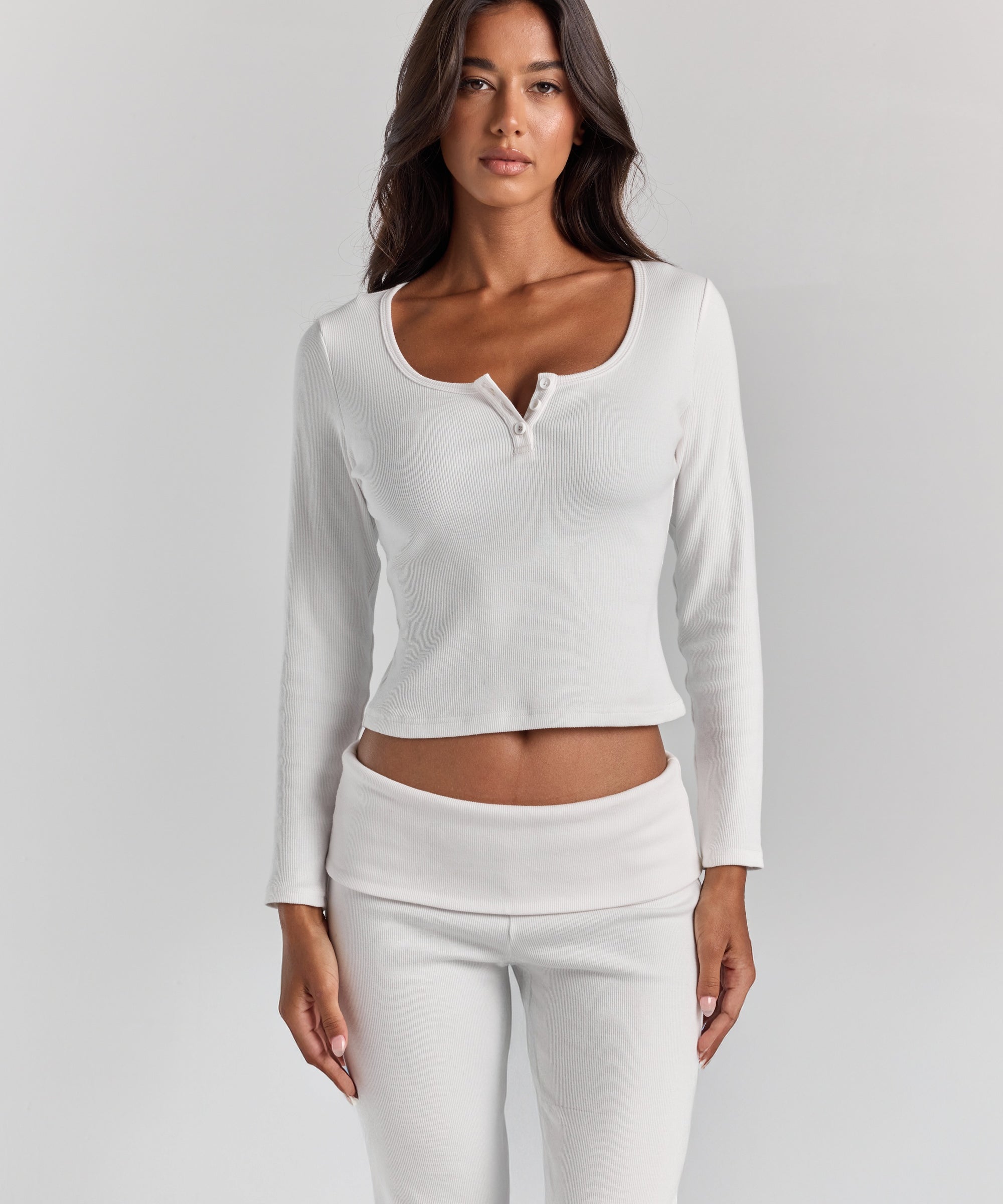ALT's white Cleo long sleeve top, fitted rib with a scoop neck and short button placket, cropped at the waist above the Frankie foldover ribbed pant.