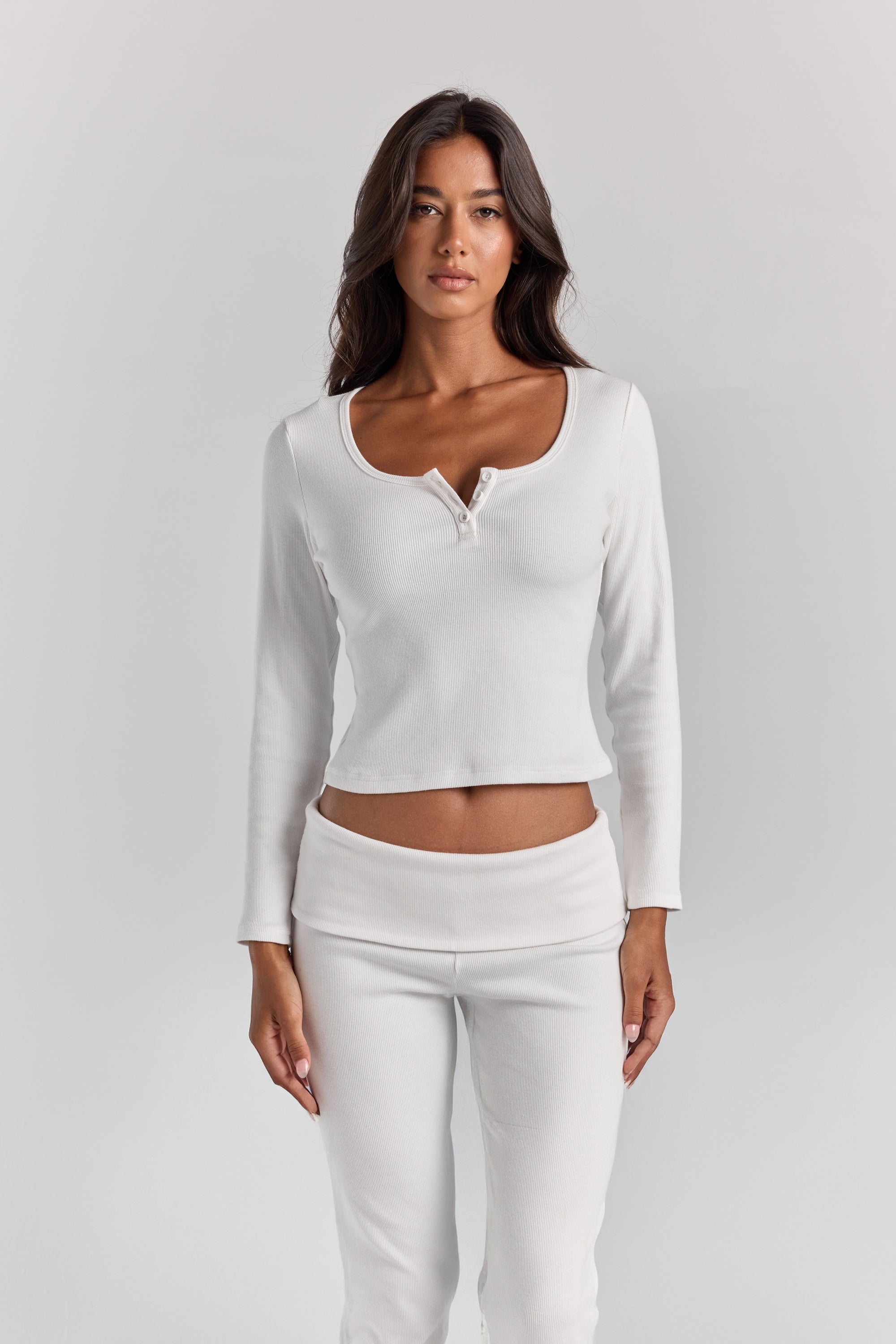 ALT's white Cleo long sleeve top, fitted rib with a scoop neck and short button placket, cropped at the waist above the Frankie foldover ribbed pant.