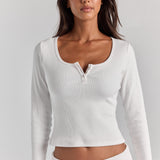 Closer front view of the white Cleo long sleeve top, with a wide scoop neck, short button placket and fitted ribbed sleeves.