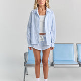 Blue stripe Corinna button-up shirt worn open over a white rib tank and the matching Beatrice short, with dropped shoulders and a hip-length hem.