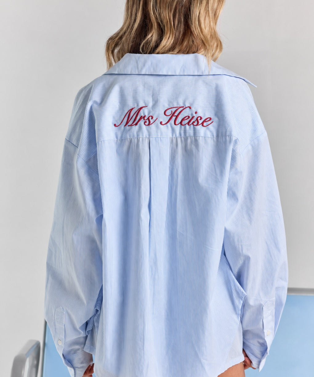 ALT's blue stripe Corinna button-up shirt from behind, with personalized embroidery across the back yoke and a center box pleat.