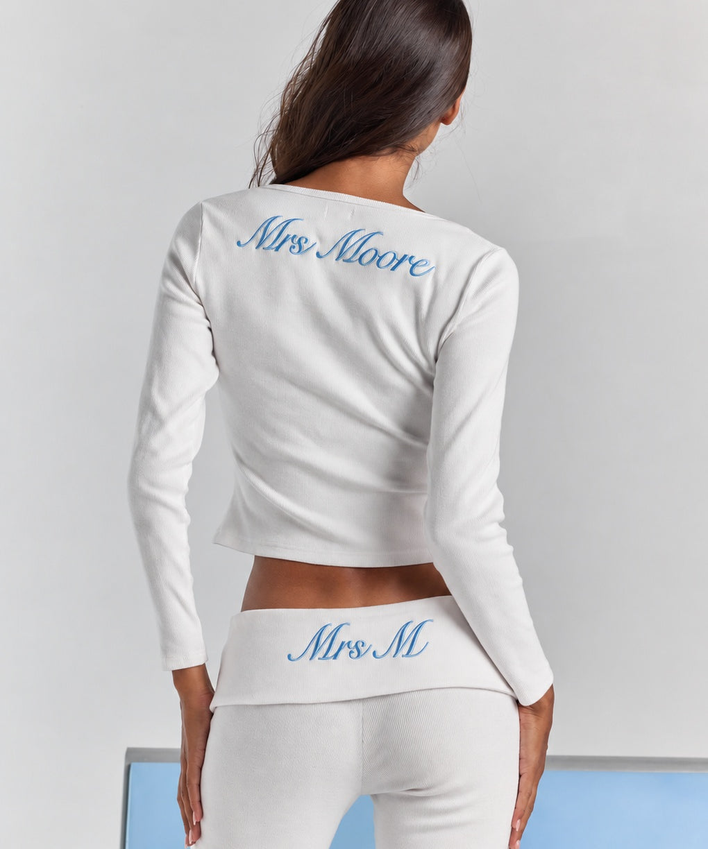 Closer view from behind of the white Frankie foldover ribbed pant, personalized embroidery on the fold-over waistband, under the Cleo long sleeve top.