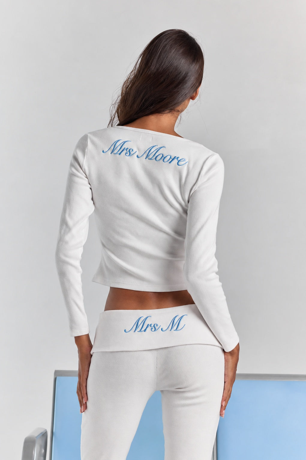 Closer view from behind of the white Frankie foldover ribbed pant, personalized embroidery on the fold-over waistband, under the Cleo long sleeve top.