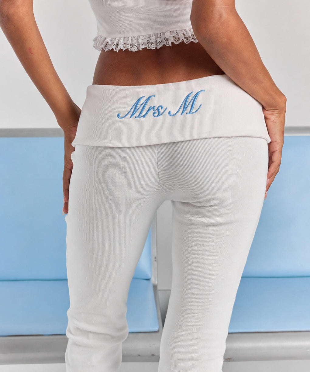 A close-up of personalized embroidery on the folded back waistband of the white Frankie foldover ribbed pant.