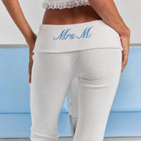 A close-up of personalized embroidery on the folded back waistband of the white Frankie foldover ribbed pant.
