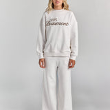 White Paola trackpant from the front at full length, a wide straight leg falling to the floor, worn with the Pia crew sweatshirt.