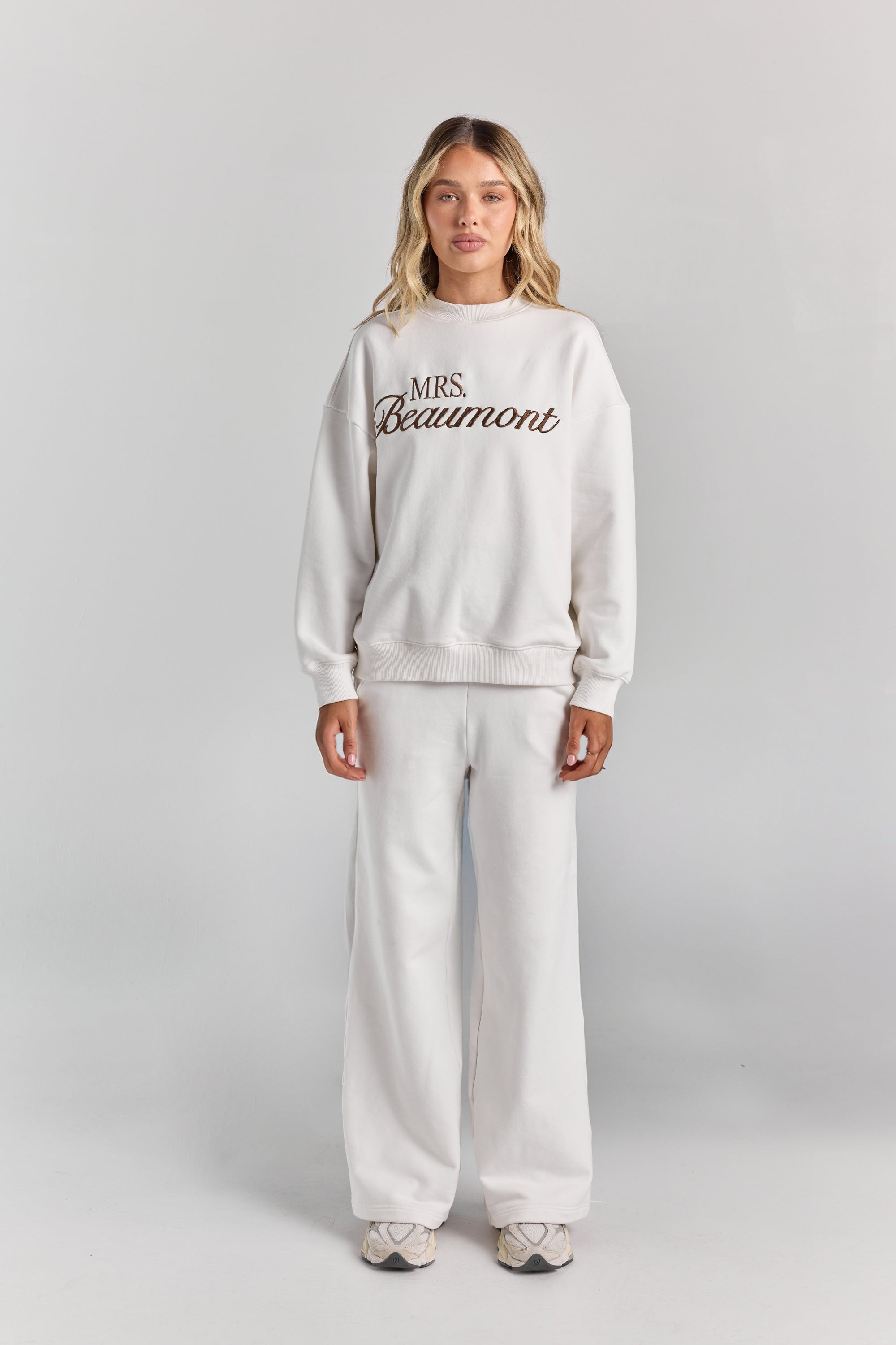 White Paola trackpant from the front at full length, a wide straight leg falling to the floor, worn with the Pia crew sweatshirt.