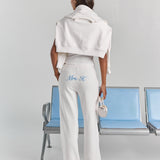White Paola trackpant from behind, with personalized embroidery across the back below the waistband and a wide straight leg.