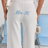 A close-up of personalized embroidery across the back of the white Paola trackpant, just below the elasticated waistband.