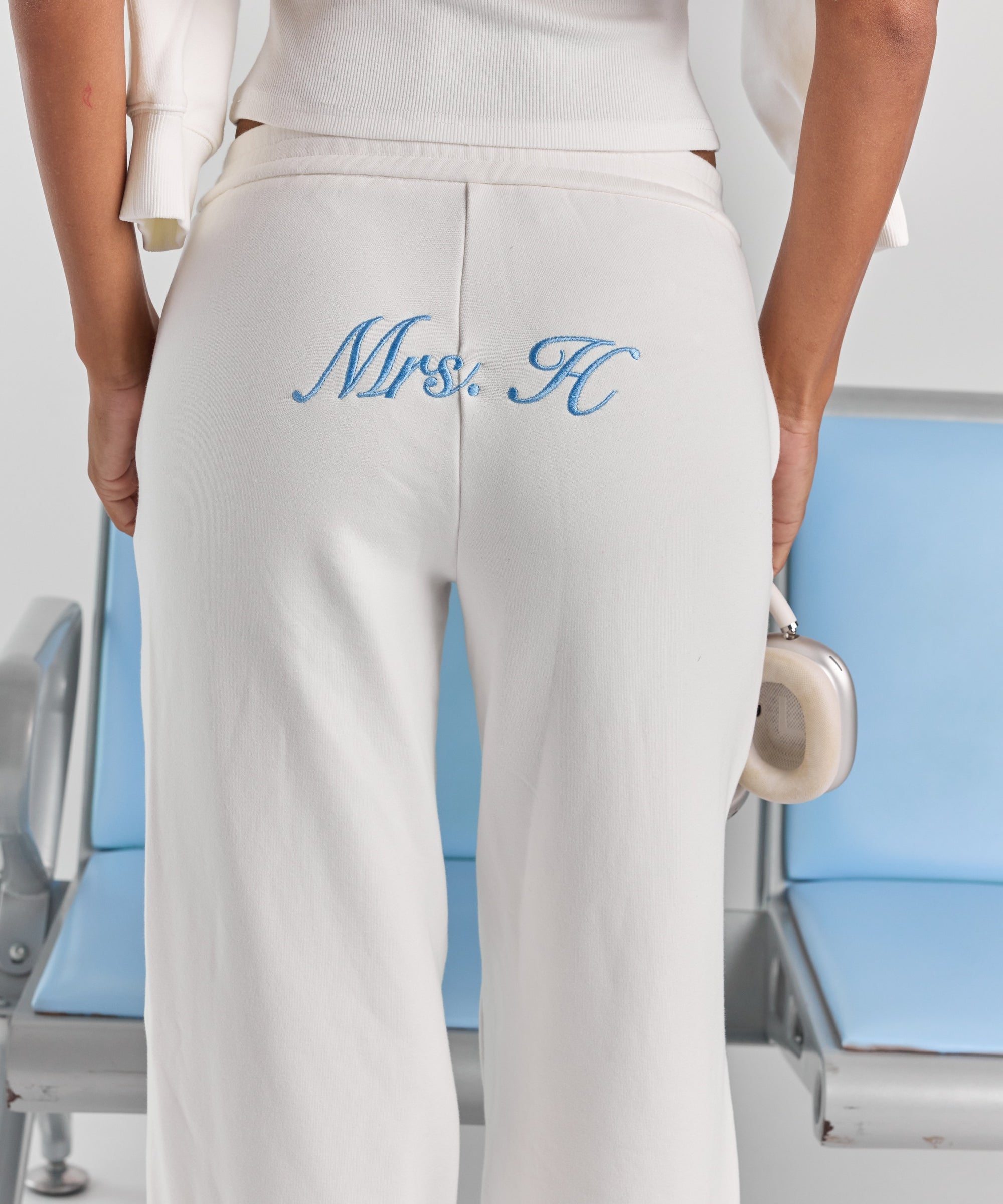 A close-up of personalized embroidery across the back of the white Paola trackpant, just below the elasticated waistband.