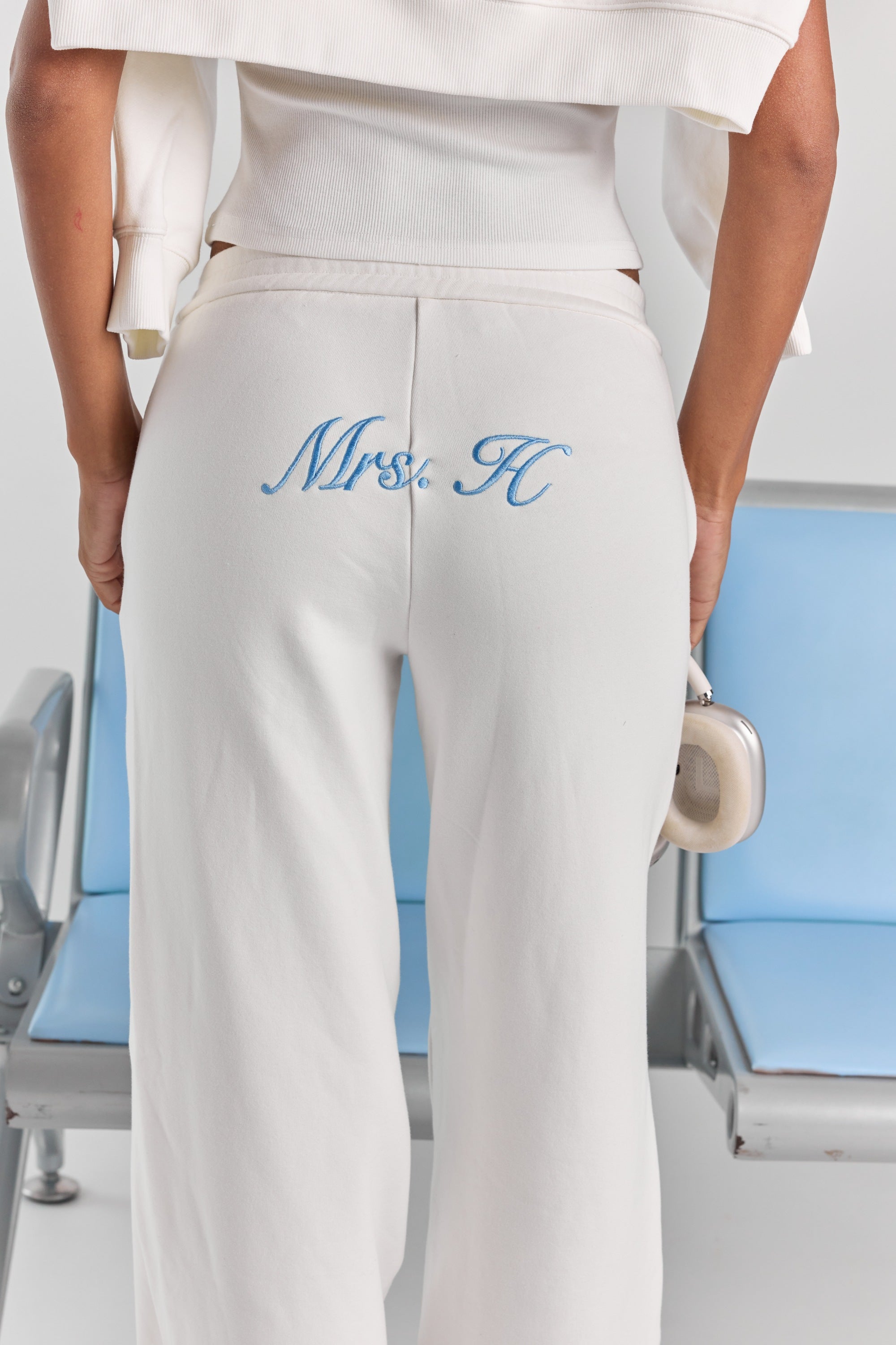 A close-up of personalized embroidery across the back of the white Paola trackpant, just below the elasticated waistband.
