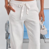 A close-up of the white Paola trackpant waist, with a satin ribbon tie, an elasticated waistband and side pockets.