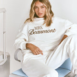 ALT's white Paola trackpant, shown seated from the front with a wide straight leg and a matching sweatshirt.