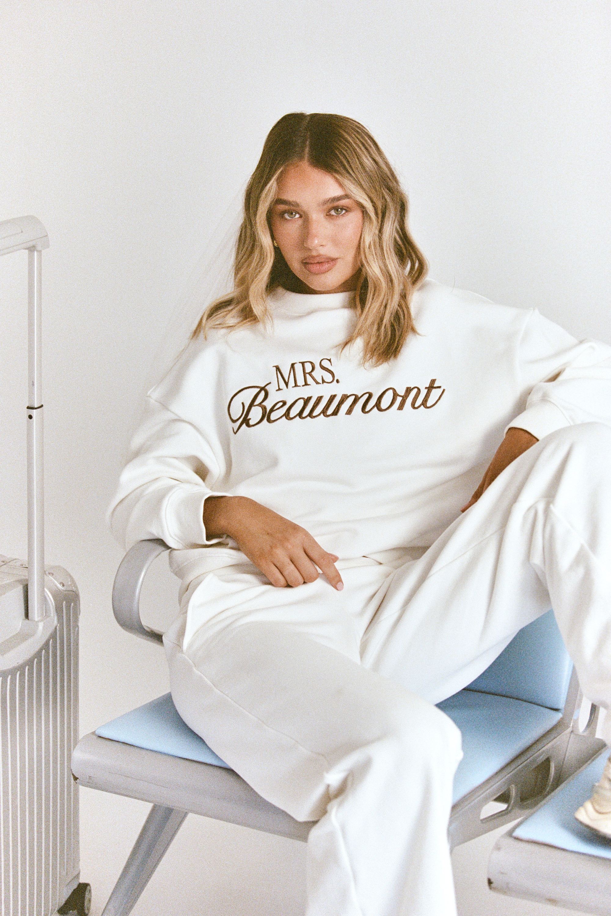 ALT's white Paola trackpant, shown seated from the front with a wide straight leg and a matching sweatshirt.