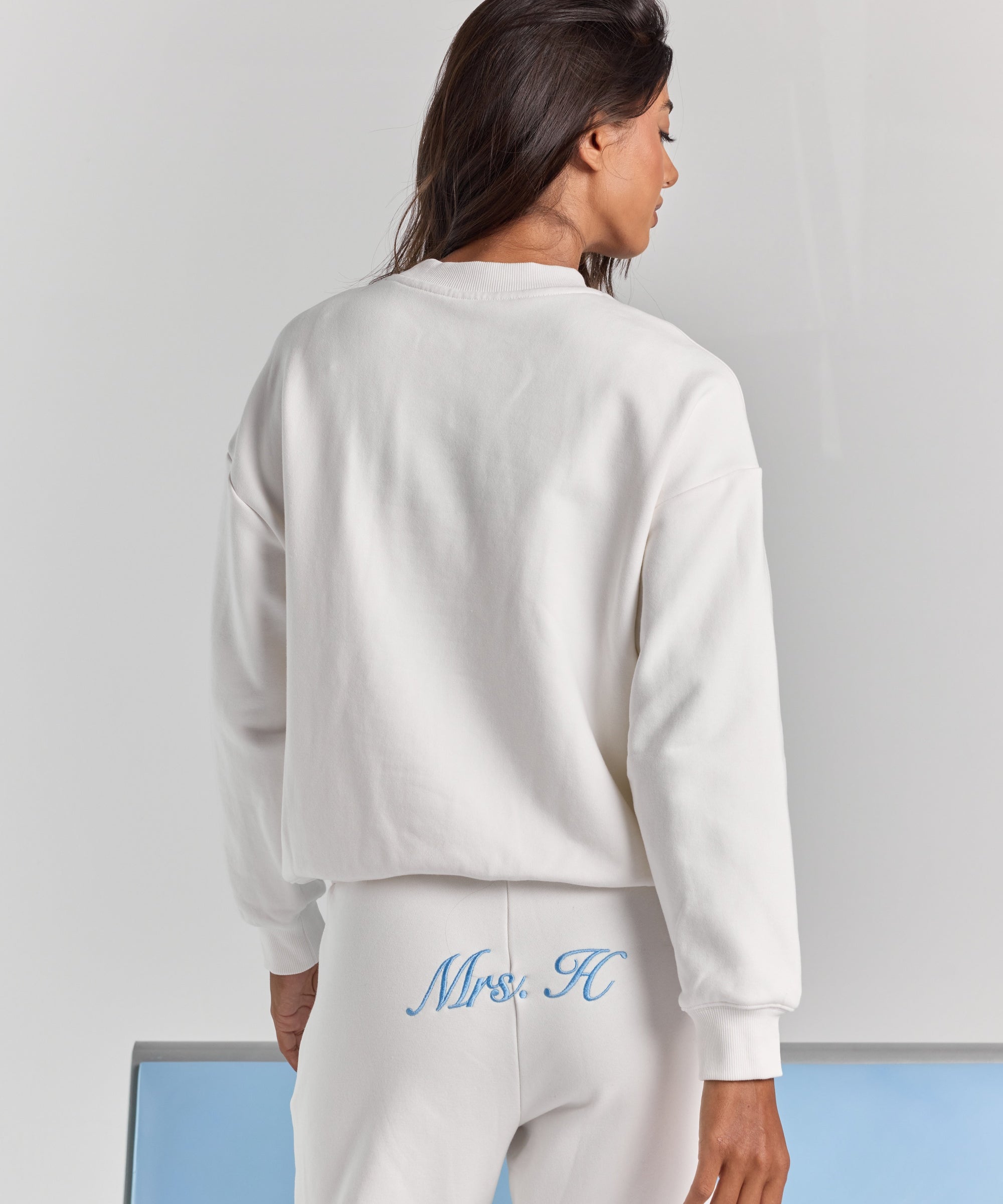 White Pia crew sweatshirt from behind, plain across the back with dropped shoulders, a ribbed neckline and ribbed cuffs.