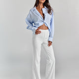 White Vivienne travel pant from a three-quarter angle, fitted through the hip with a straight leg that flares slightly at the hem.