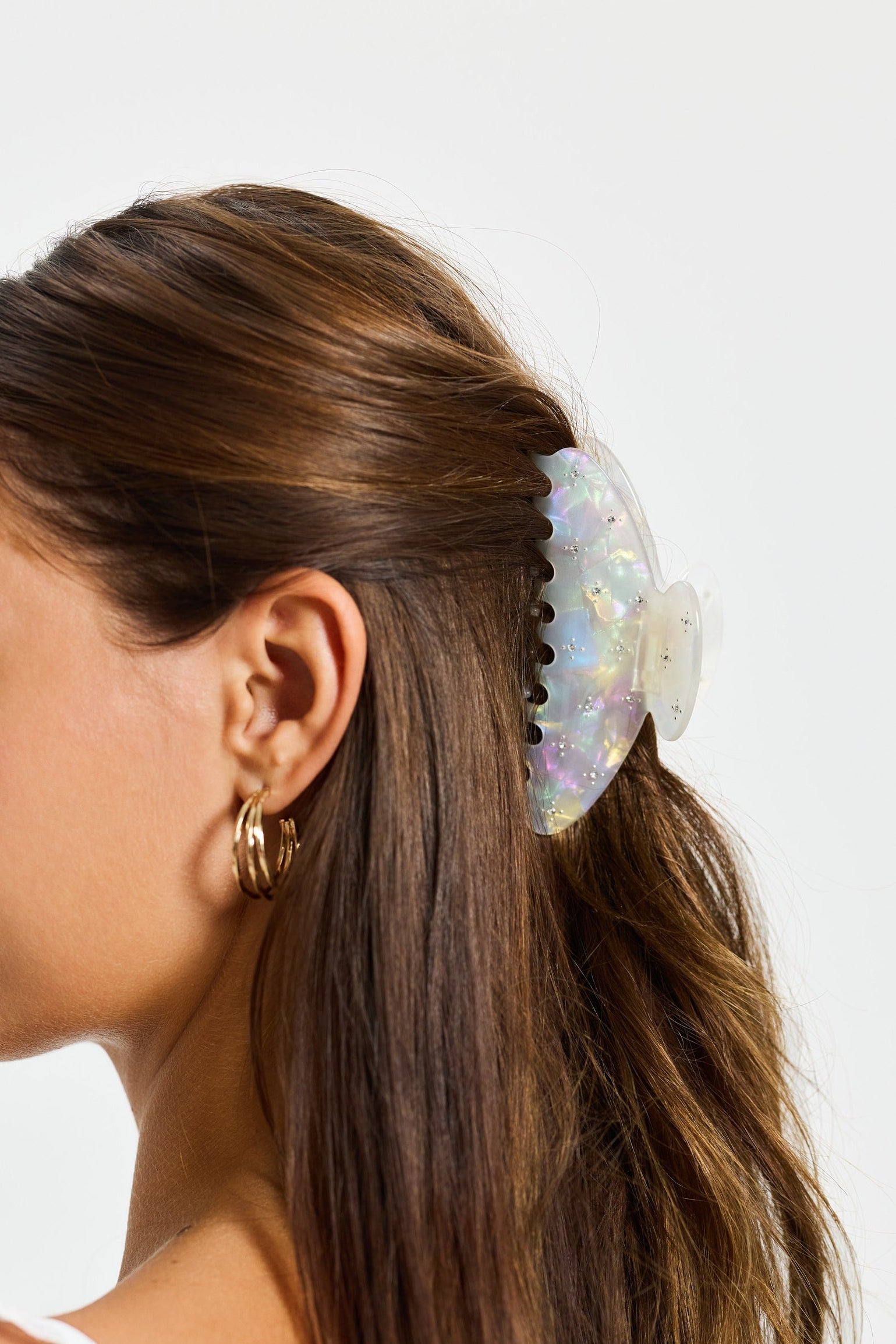 ALT's iridescent Gia claw clip, worn in the hair from the side, the iridescent finish catching the light.
