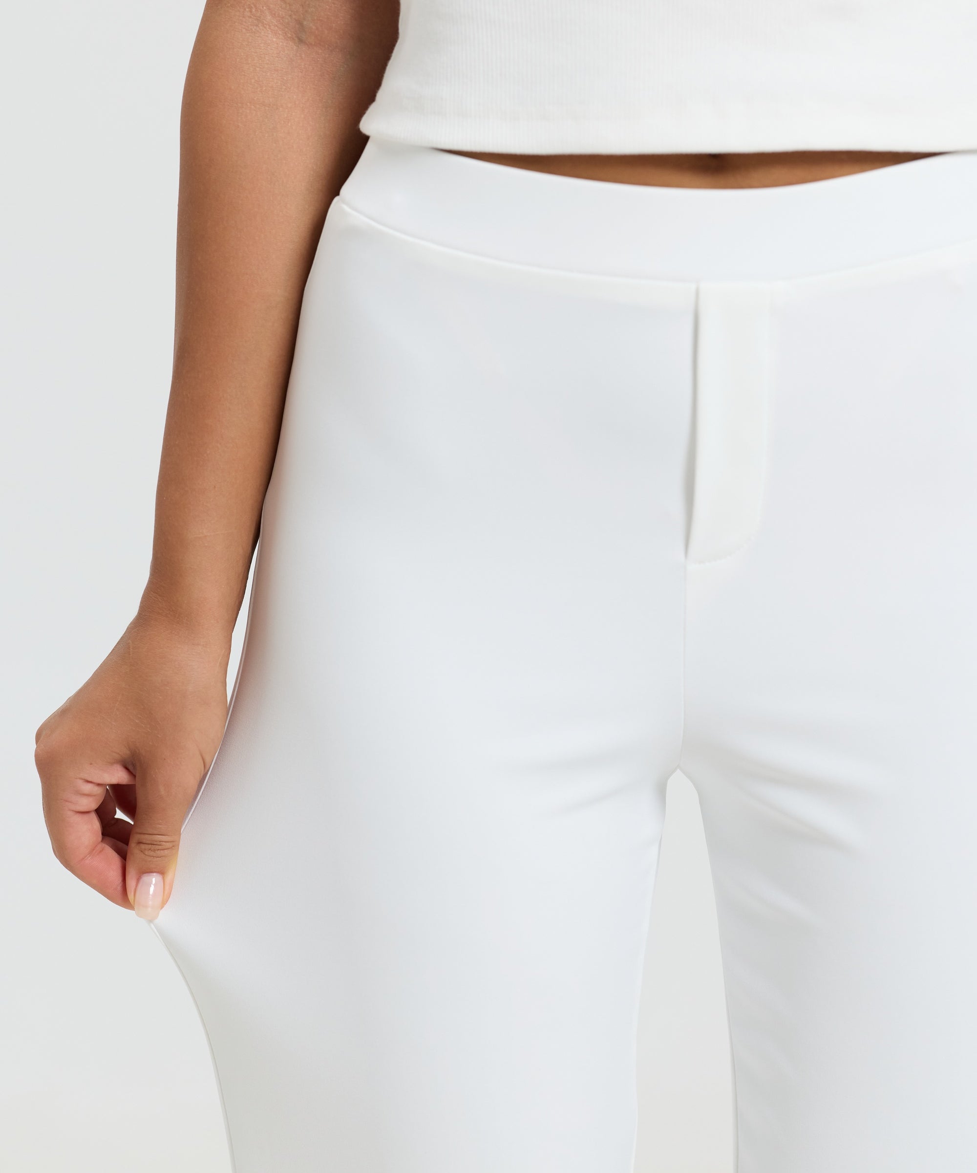 A close-up of the flat front waistband and pressed front seam of ALT's white Vivienne travel pant.