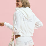ALT's white Wifey rhinestone velour zip hoodie, seen from behind with BRIDE in rhinestones across the back and the hood down.
