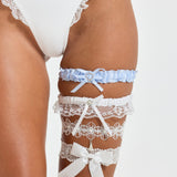 ALT's white Zoe garter, worn on the thigh with pearl-set floral lace and a teardrop drop, stacked with three others.