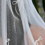 Woman wearing ALT’s Roma top, Margot bottom, Belle Bow veil. a white bridal bikini set, with cacti in the background. White tulle bridal veil with small bow details