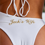 Woman wearing ALT’s Elidy one piece, a white bridal one piece swimsuit with gold chain halter detailing, back tie and gold embroidery Jack's Wife