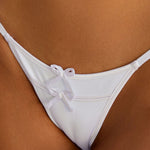 Woman wearing ALT’s Kala top and Faya bottom, a white bridal bikini set, with cactus behind her. Small satin bow and satin binding. 