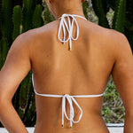 Woman wearing ALT’s Kala top and Faya bottom, a white bridal bikini set, with cacti in the background. Small satin bow and satin binding. Gold embroidery on the back of the bottoms Mrs. M