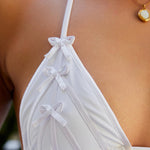 Woman wearing ALT’s Kala top and Faya bottom, a white bridal bikini set, with cacti in the background. Small satin bow and satin binding