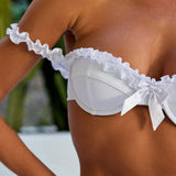 Woman wearing ALT’s Roma top and Margot bottom, a white bridal bikini set, with cacti in the background. Satin frill detailing and bow