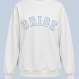 ALT's white Bride Pia crew sweatshirt shown on its own from the front, with BRIDE in blue-outlined varsity applique across the chest.